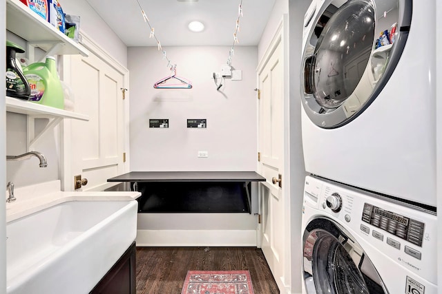 clothes washing area featuring dark wood-style floors, laundry area, stacked washing maching and dryer, and a sink