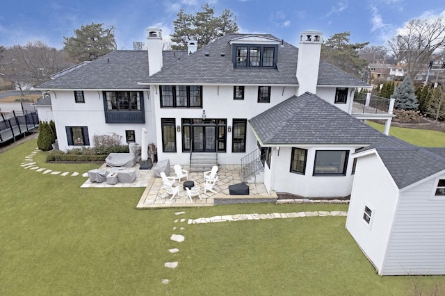 rear view of house with a yard, stucco siding, a chimney, and a patio area