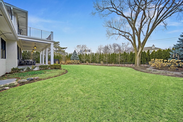 view of yard featuring a patio, a balcony, and a ceiling fan