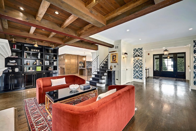 living area with beam ceiling, dark wood-style floors, stairs, and a decorative wall