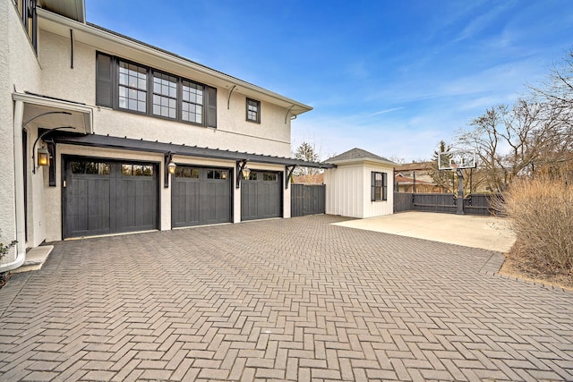 garage with decorative driveway and fence