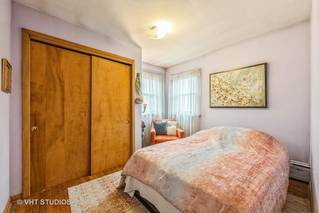 bedroom featuring a closet, baseboard heating, and wood finished floors