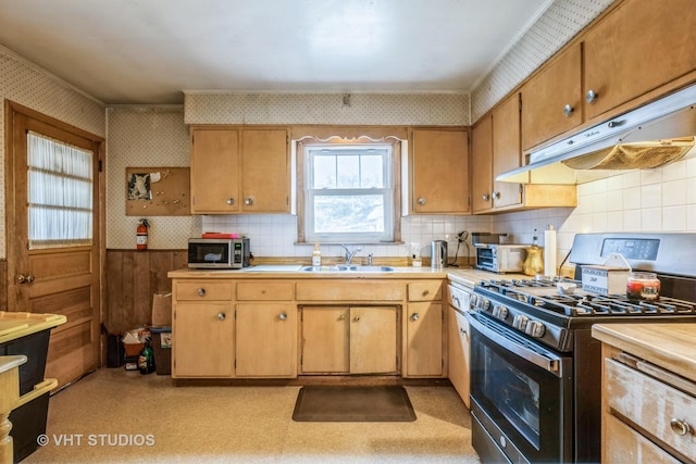 kitchen with a sink, under cabinet range hood, appliances with stainless steel finishes, wallpapered walls, and light floors