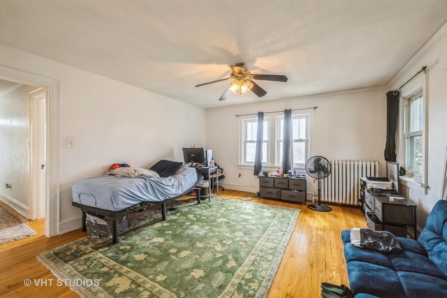 living room featuring baseboards, radiator, light wood-style flooring, and a ceiling fan