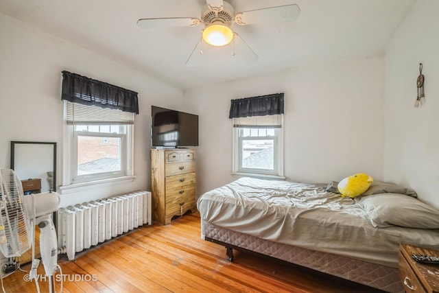 bedroom featuring a ceiling fan, light wood-style flooring, and radiator heating unit