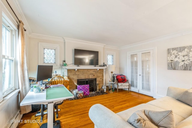 living room featuring wood finished floors, a fireplace, ornamental molding, french doors, and baseboard heating