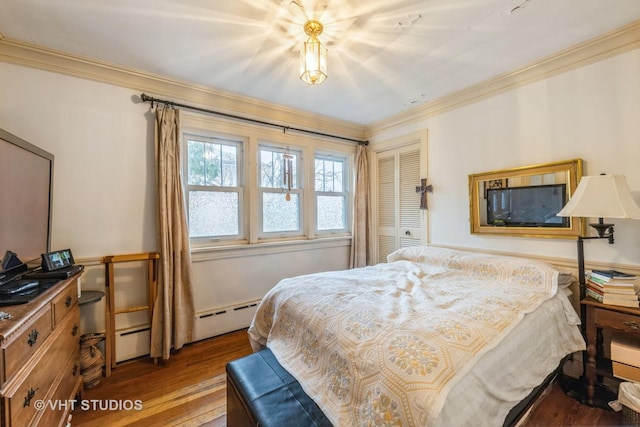 bedroom featuring ornamental molding, hardwood / wood-style flooring, a closet, a baseboard heating unit, and baseboard heating