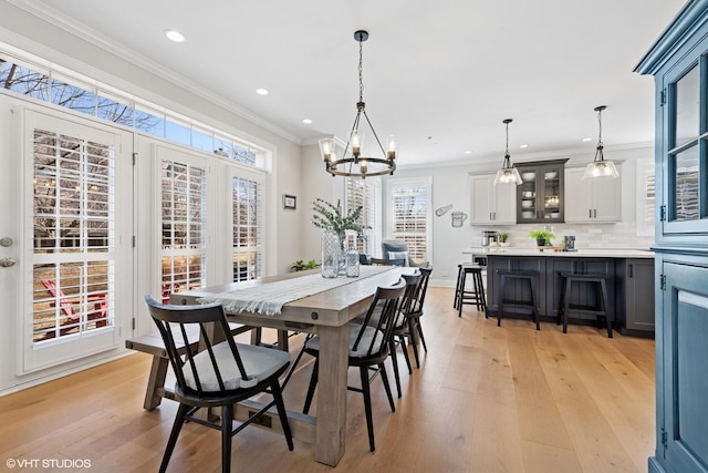 dining room featuring light wood-type flooring, an inviting chandelier, crown molding, and recessed lighting