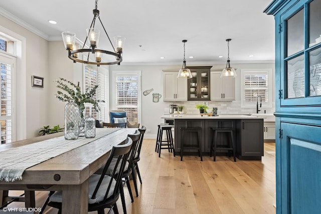 dining area featuring ornamental molding, light wood-type flooring, an inviting chandelier, and recessed lighting