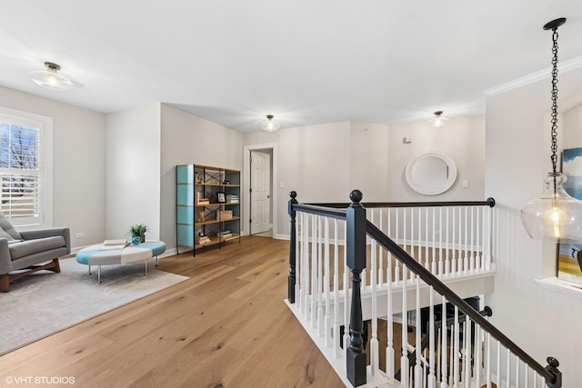 hallway with baseboards, an upstairs landing, and wood finished floors