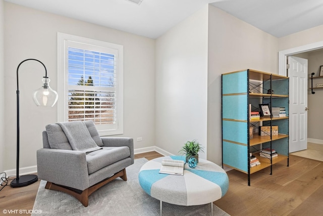 living area with baseboards and wood finished floors