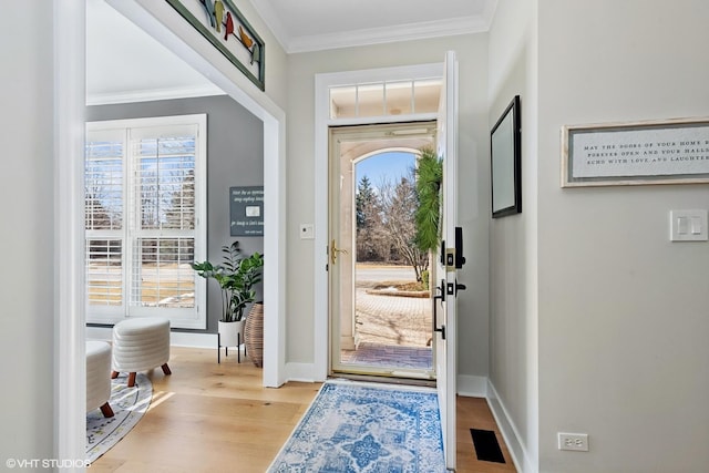 foyer entrance with baseboards, crown molding, and wood finished floors