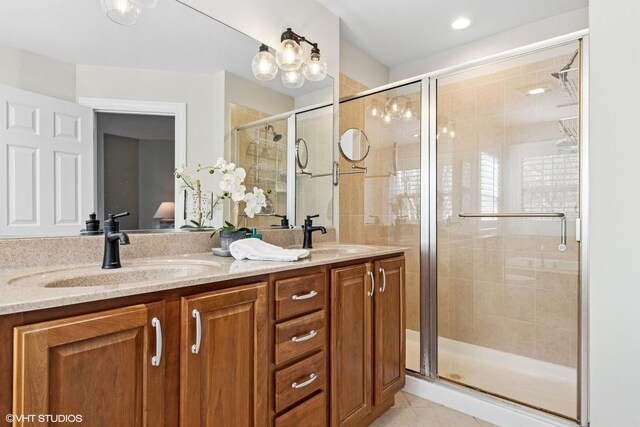 bathroom featuring a stall shower, tile patterned flooring, a sink, and double vanity