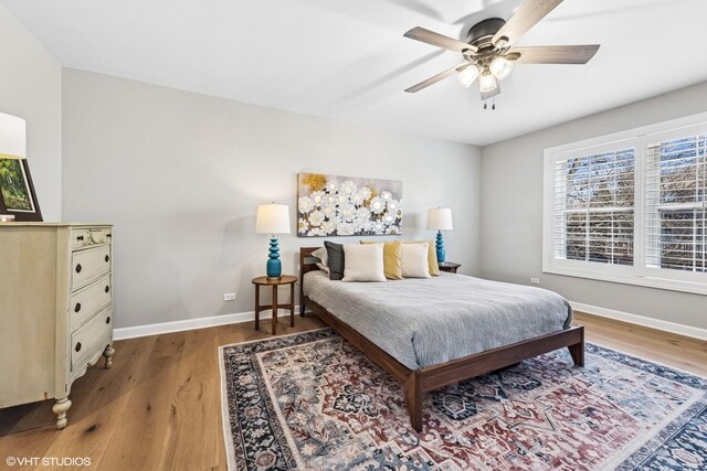 bedroom with ceiling fan, wood finished floors, and baseboards