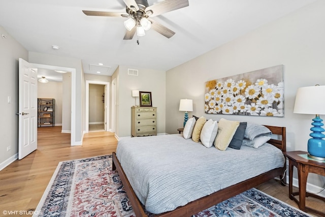 bedroom with visible vents, light wood-style flooring, attic access, ceiling fan, and baseboards