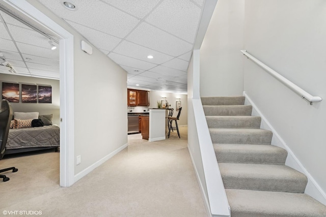 stairs featuring carpet, a paneled ceiling, and baseboards