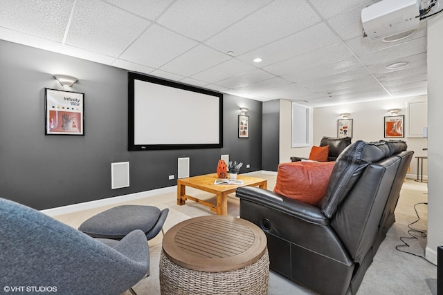 cinema featuring an AC wall unit, a paneled ceiling, light colored carpet, and baseboards