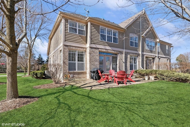 rear view of house with a yard, a patio, and brick siding