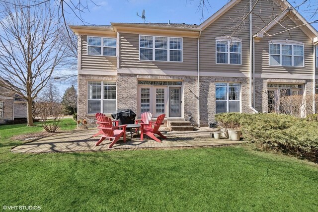 rear view of house featuring brick siding, a lawn, and a patio