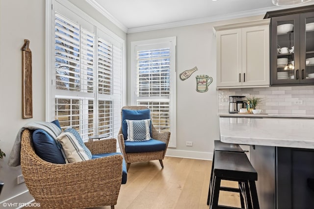 sitting room featuring baseboards, light wood-type flooring, and crown molding