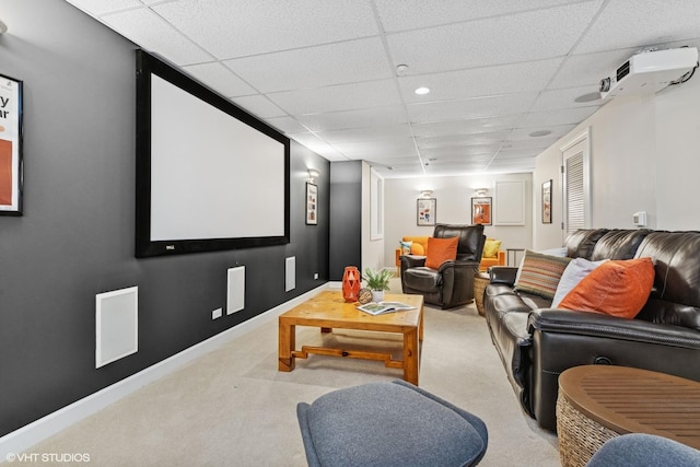 carpeted cinema room with a paneled ceiling and baseboards