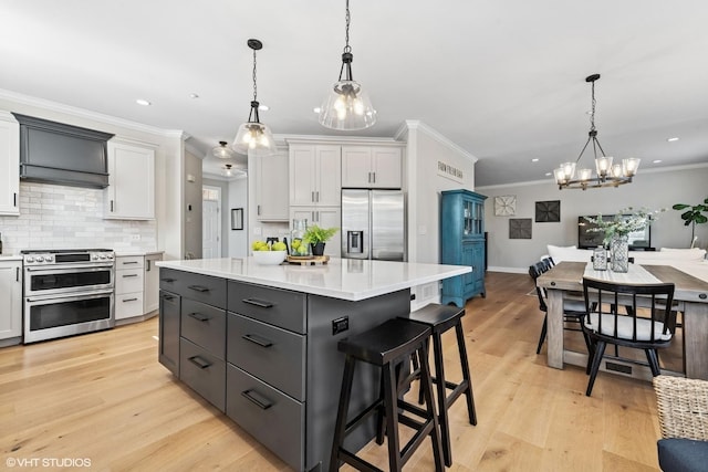 kitchen featuring light wood-style flooring, appliances with stainless steel finishes, decorative backsplash, and light countertops