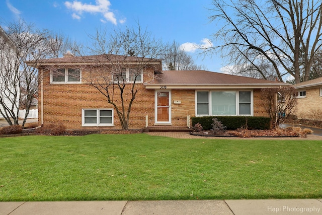 tri-level home with brick siding and a front yard