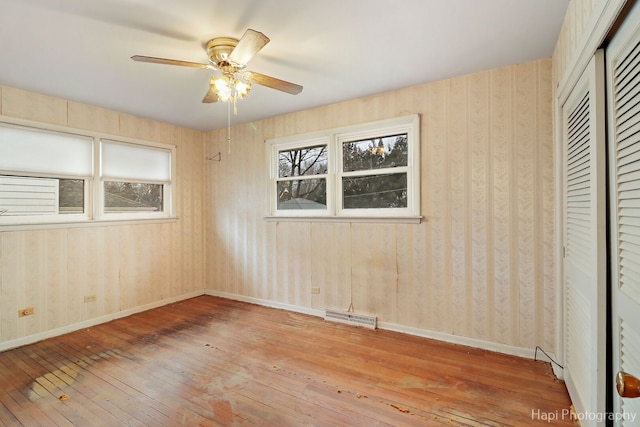 unfurnished bedroom with hardwood / wood-style flooring, a closet, visible vents, and baseboards