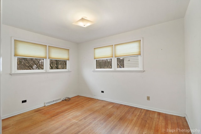 empty room with light wood-type flooring, a healthy amount of sunlight, baseboards, and visible vents