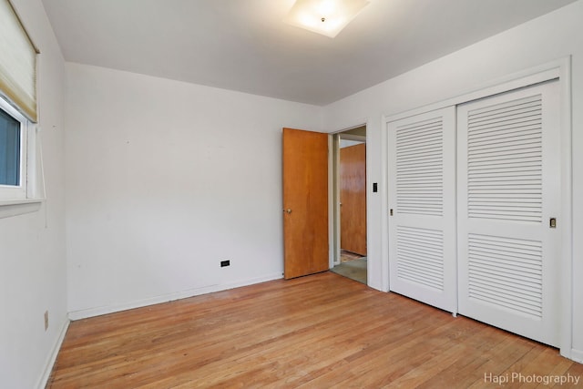 unfurnished bedroom with light wood-style flooring, baseboards, and a closet