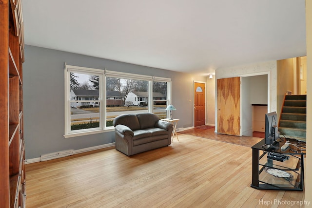 living area featuring wood-type flooring, visible vents, stairway, and baseboards