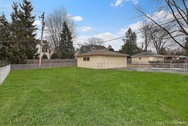 view of yard featuring a fenced backyard, a detached garage, and an outbuilding