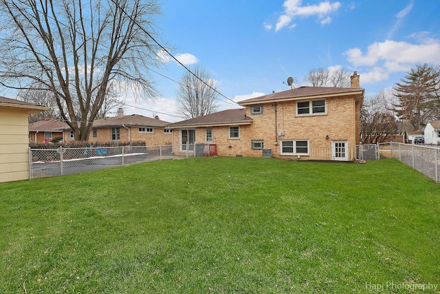 back of house with a yard, brick siding, a chimney, and a fenced backyard