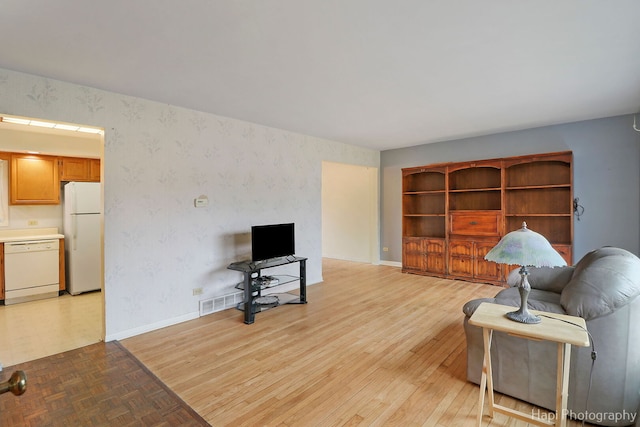 living room featuring wallpapered walls, parquet flooring, and baseboards