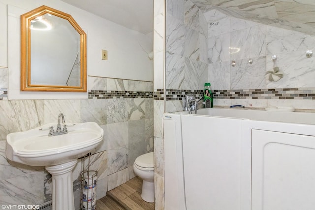 bathroom with toilet, tile walls, and wood finished floors