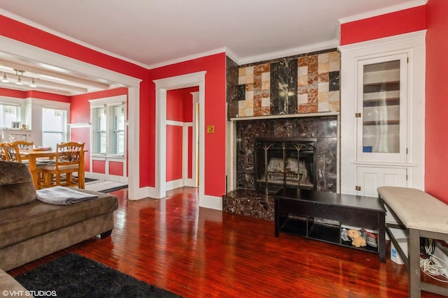 living room featuring baseboards, a premium fireplace, wood finished floors, and crown molding