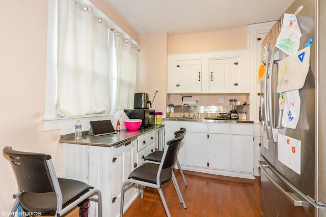 kitchen with stainless steel countertops, white cabinetry, a sink, and stainless steel fridge with ice dispenser