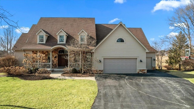 cape cod home with stone siding, aphalt driveway, a porch, and a front yard