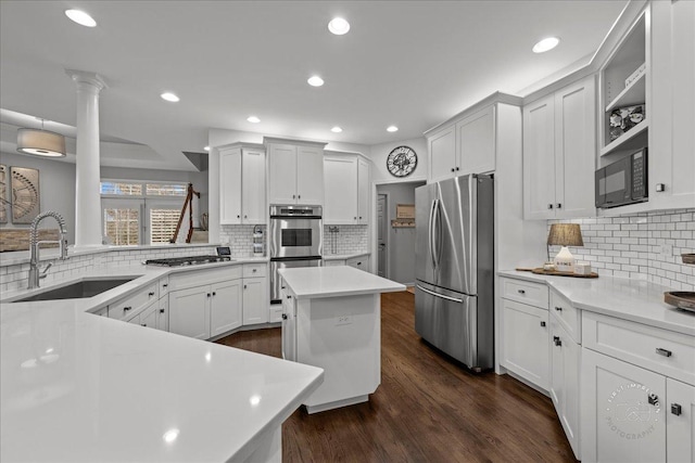 kitchen with stainless steel appliances, light countertops, dark wood-type flooring, white cabinetry, and a sink