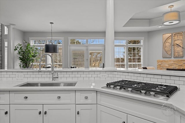 kitchen featuring a healthy amount of sunlight, stainless steel gas stovetop, light countertops, and a sink