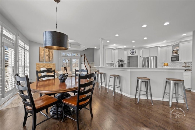 dining room featuring dark wood-style floors, a stone fireplace, baseboards, and recessed lighting