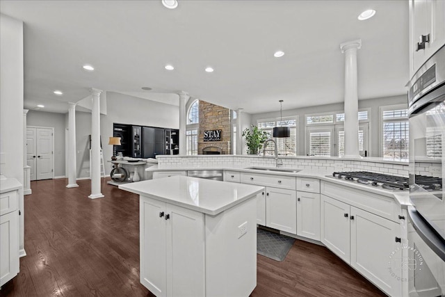 kitchen with dark wood-style floors, decorative columns, stainless steel appliances, and a sink