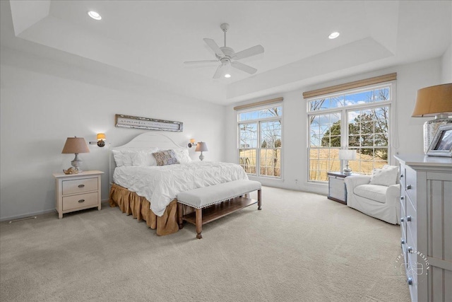 bedroom featuring light carpet, a tray ceiling, a ceiling fan, and recessed lighting