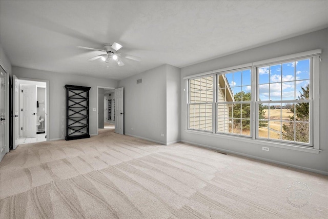 spare room featuring baseboards, ceiling fan, visible vents, and light colored carpet