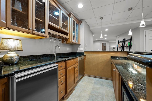 kitchen with brown cabinetry, dishwasher, stainless steel dishwasher, pendant lighting, and a sink