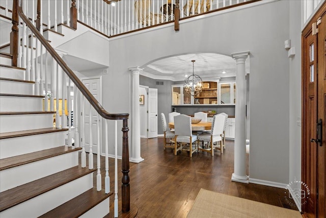 foyer with ornate columns, baseboards, arched walkways, and wood finished floors