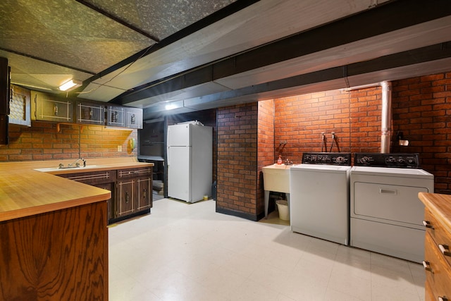 finished basement with light floors, freestanding refrigerator, and brick wall