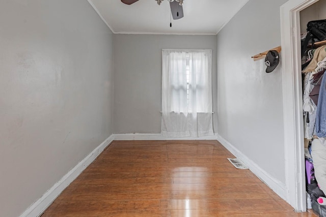 unfurnished room with baseboards, visible vents, wood finished floors, and ornamental molding