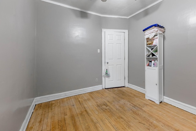 empty room with ornamental molding, hardwood / wood-style floors, and baseboards