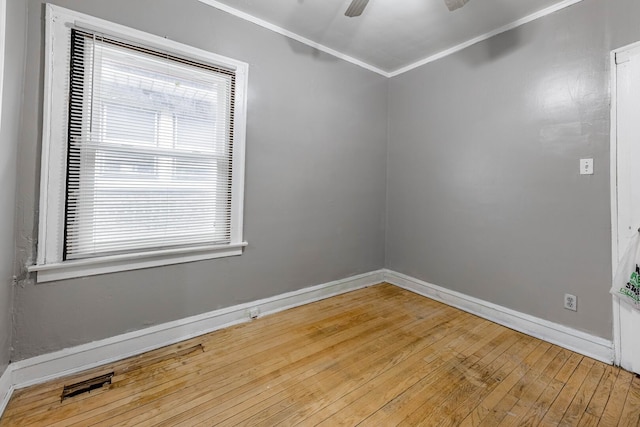 unfurnished room with ornamental molding, wood-type flooring, visible vents, and baseboards